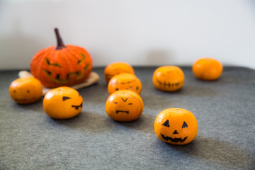 Halloween oranges painted as spooky evil and evil pumpkin on grey carpet and white background