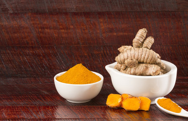 Turmeric roots and turmeric powder in white bowl - Curcuma longa
