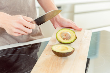 A man cutting avocado with sharp knife on chopping board