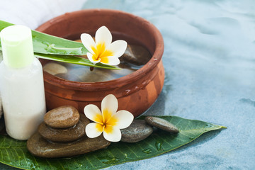 Obraz na płótnie Canvas Spa or wellness flowers with tropical leaves and stones. Body care and spa concept on blue