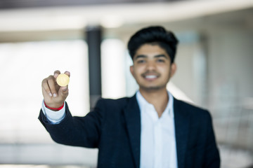 Fototapeta premium Indian business man in suit with golden bitcoin in modern office