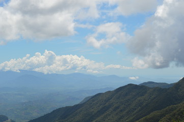 Green hill with the sky and clouds in the horizon. Trees and clouds in the background.Big white clod in the horizon.