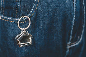 Fototapeta na wymiar House shape keychain or key holder in a jeans pocket. Concept of own a house and home financing