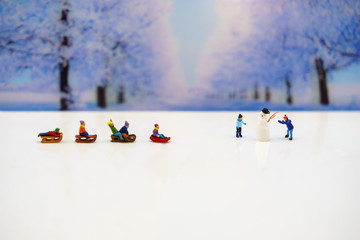 Miniature people: Childrens playing fun with snow slider.