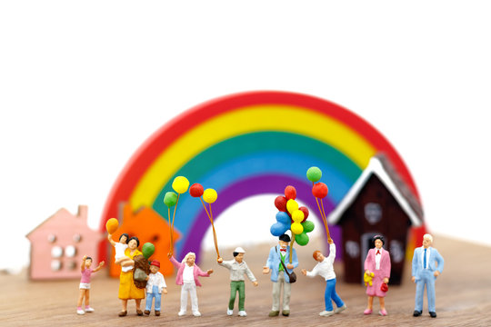 Miniature people: family and children enjoy with colorful balloons, house and rainbow, happy family day concept.