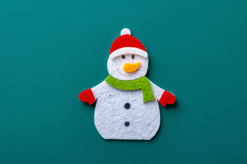 flat smiling toy christmas snowman with green scarf on green background