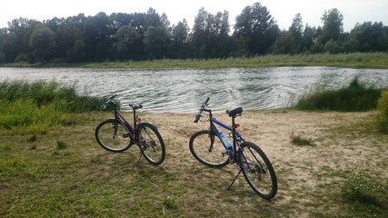 Two mountain bikes next to a lake - obrazy, fototapety, plakaty