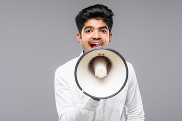 Young indian Businessman announcing into a megaphone isolated on gray background
