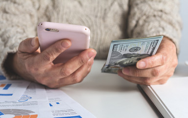 North american currency: Dollar. Old woman counting bills on table.