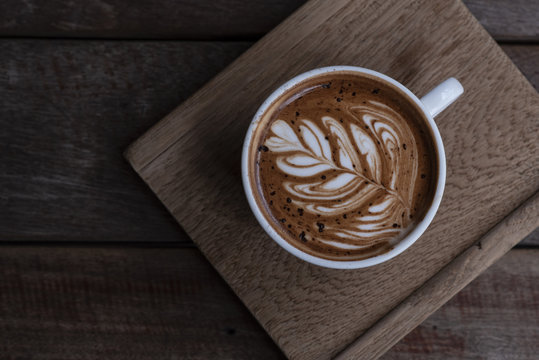 Nice shape of latte art coffee serve on wooden plate