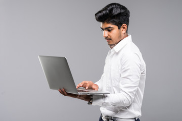 Young indian man with laptop isolated on gray background