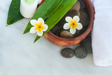 Fototapeta na wymiar Top view of spa objects and stones for massage treatment on white background fith flowers.