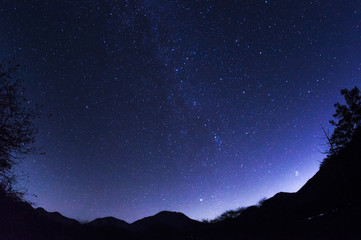 魚眼レンズで撮影した山の上に注ぐ星空