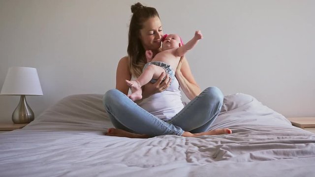 A Portrait of a beautiful mother with her 2 month old baby in the bedroom