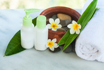 Obraz na płótnie Canvas Spa or wellness setting with tropical flowers with sunlight, towel and cream tube. Body care and spa concept