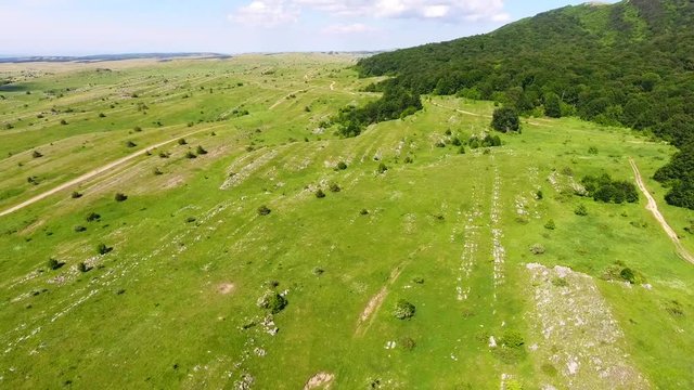 Cinematic drone shot flying in Crimea mountains fields green hills,road in Karabi summer sunny 4K over a road, beautiful forest, authentic view, hiking style travel story.