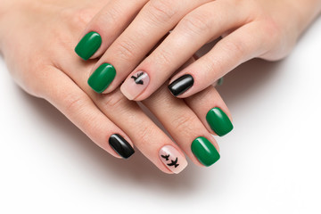 Obraz na płótnie Canvas green black manicure with painted black flying birds on square short nails on a white background close-up