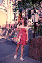 Happy student. Dark-haired happy student wearing nice red summer dress heading to the university with her transparent bag