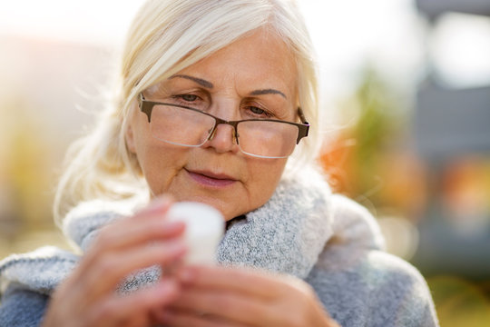 Senior woman taking prescription medicine outdoors
