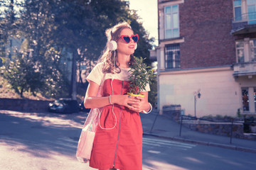 Obraz premium Beautiful shopaholic. Beautiful shopaholic feeling happy and satisfied while crossing street with new home plant