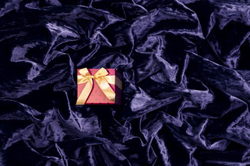 Pink gift box on a delicate blue silk surface with highlights, arranged in waves and pleats