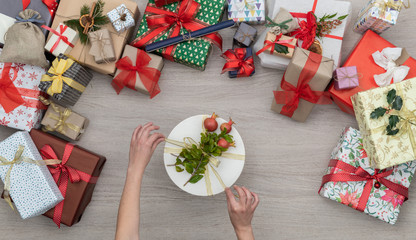 Hands with gift present box in vertical top view wooden table full of christmas or birthday gifts presents.Xmas winter holiday season party social media card background,portrait story