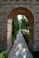 A brick archway over a sidewalk leading into the distance.