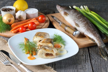 Baked pike with vegetables. Baked pike with carrots and onion near raw fish ready for cooking.