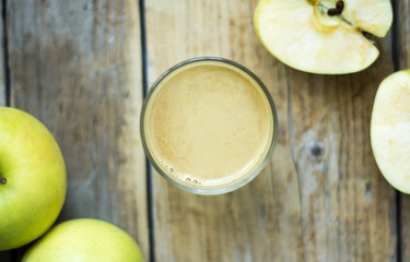 Homemade fresh squeezed apple juice in a clear glass with apple on a side