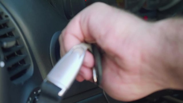 Man's hand puts key in ignition and remove key from it