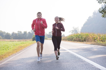 young couple jogging along a country road