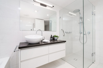 Naklejka na ściany i meble Large modern bathroom interior with floor to ceiling tiling and luxury fittings.