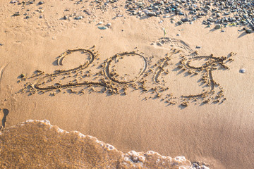 2019 - the date of the new year is written on the yellow sand by the sea or ocean. The concept of the New Year holidays and the onset of the new year twenty nineteen. Background