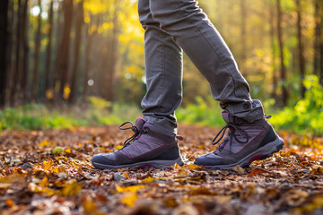 Woman is wearing hiking boot and walking in forest at autumn. 