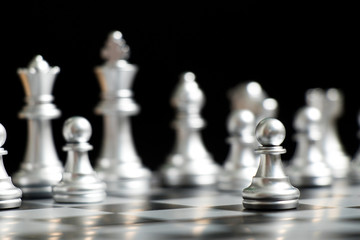 Silver pawn is on the first move in chess game on black background (Concept for business decision, start or beginning project)