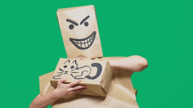 concept of emotion, gestures. a man with a package on his head, with a painted smiley angry, sly, gloating and stroking a cat painted on a box.