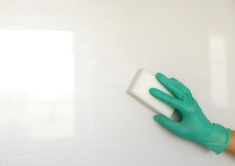 Woman hand in protective green gloves cleaning white kitchen