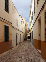 Fototapeta na wymiar a long straight cobbled picturesque empty narrow street of old houses in cuitadella menorca