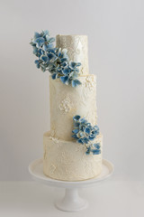 Elegant 3 Tier Wedding Cake With Piped Lace Accents And Edible Floral Bouquet.