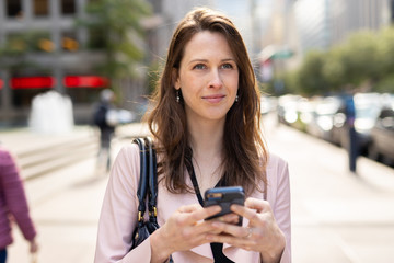 Fototapeta premium Business woman in city walking using cell phone