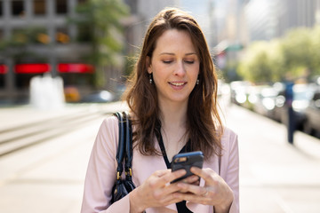 Business woman in city walking using cell phone