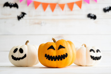White and yellow ghost pumpkins with witch hat on white wooden borad background with bat. halloween concept.