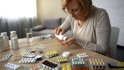 Old female taking capsules from bottle self-medication pills addiction obsession - obrazy, fototapety, plakaty