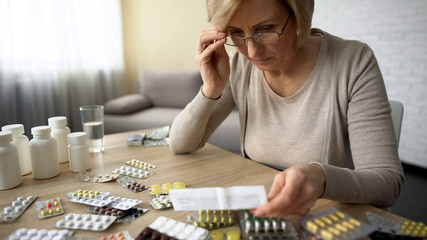 Retired female in glasses reading medicine instruction, pharmaceutical industry