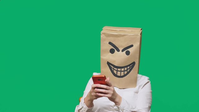 concept of emotions, gestures. a man with a package on his head, with a painted black emoticon, crafty, gloating, talking on a mobile phone.
