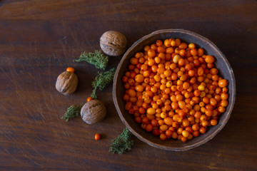 Seabuckthorn and nuts on dark wood background