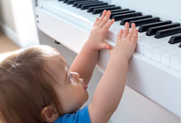Toddler boy excited to reach up and play the piano