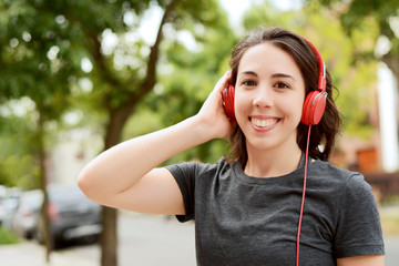 Portrait of young beautiful woman with red headphones listening music