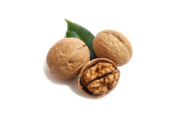 Three walnuts and a green leaf on a white isolate background