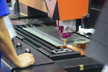 The CNC fiber laser cutting machine cutting the sheet metal plate  with the sparking light. Modern sheet metal manufacturing process.